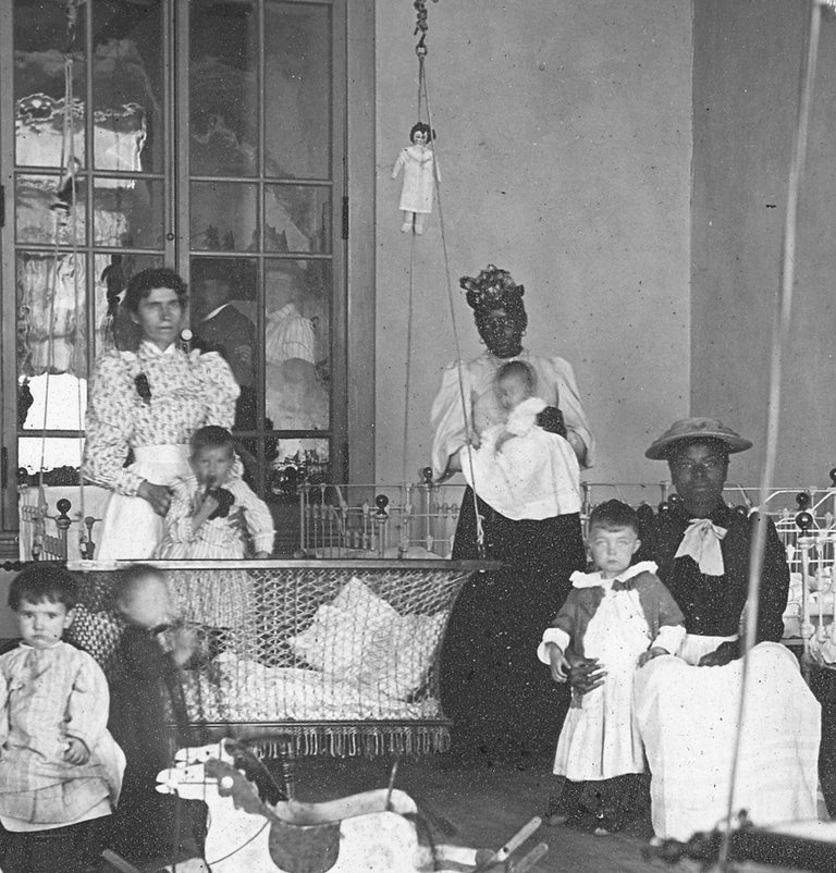 [3729042] [Glass Lantern Slide Showing African American Women Caretakers in a Day Nursery with White Children]. Manufacturing Optician T H. McAllister.
